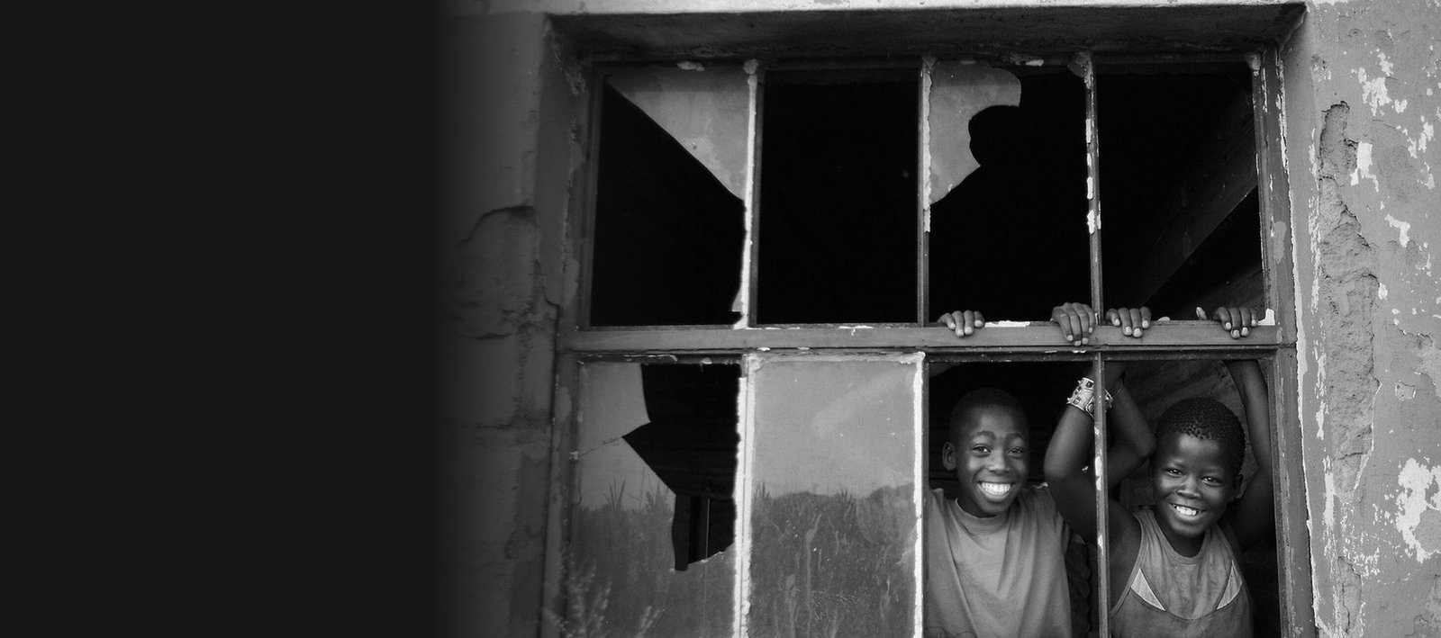 Two boys leaning out of a broken farm window, Children of Geluk No.1 by Martin Osner