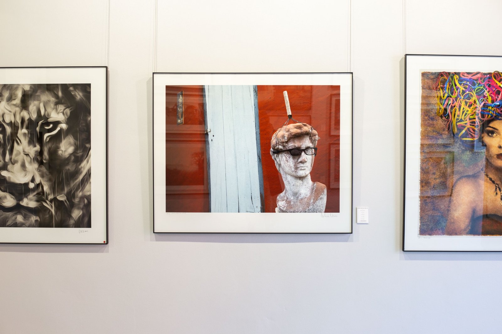 Dawid van die Wolwe by Martin Osner, a David statue in sunglasses against a red wall, framed on a gallery wall