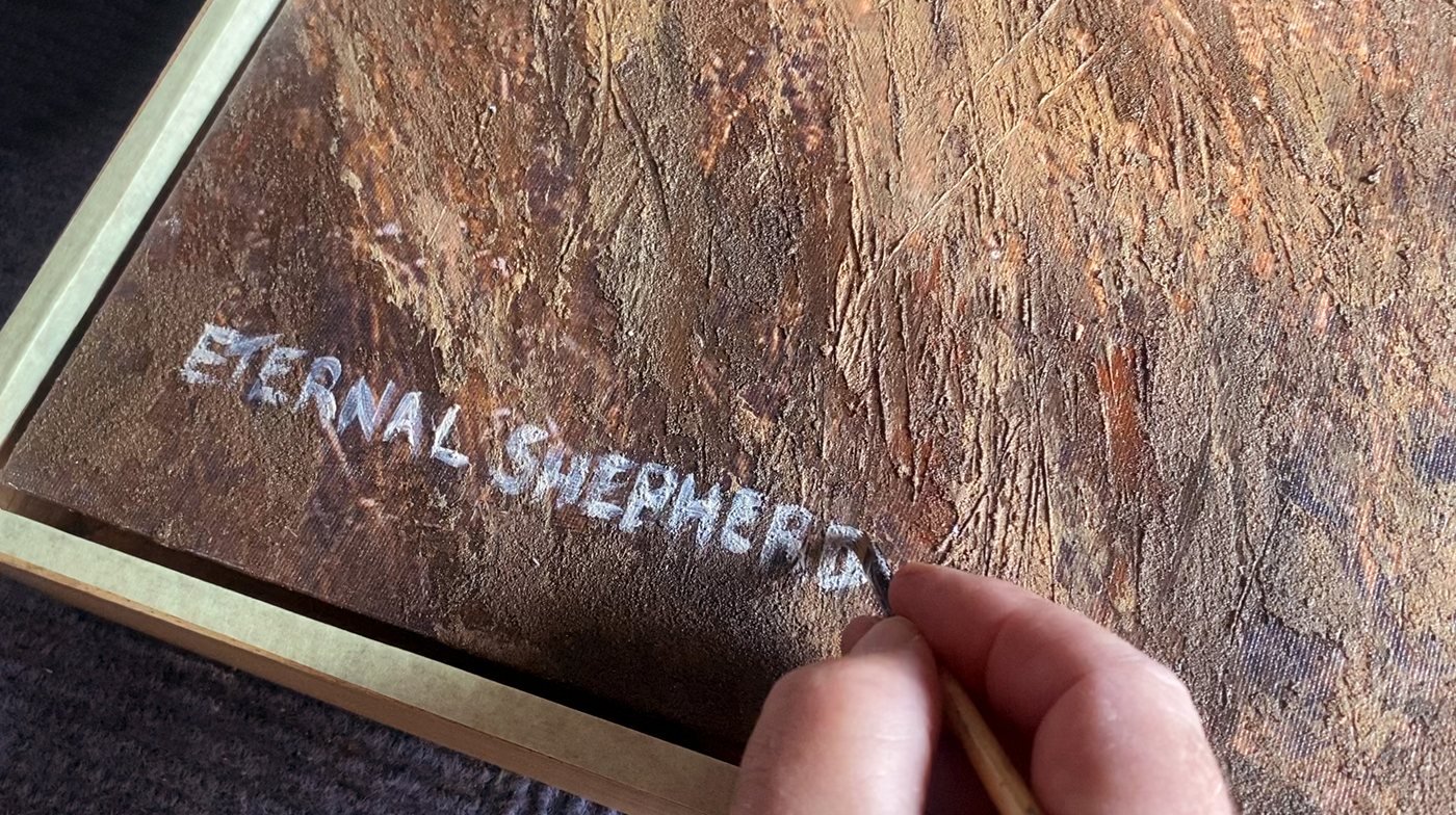Martin Osner painting the title Eternal Shepherd onto the canvas by hand